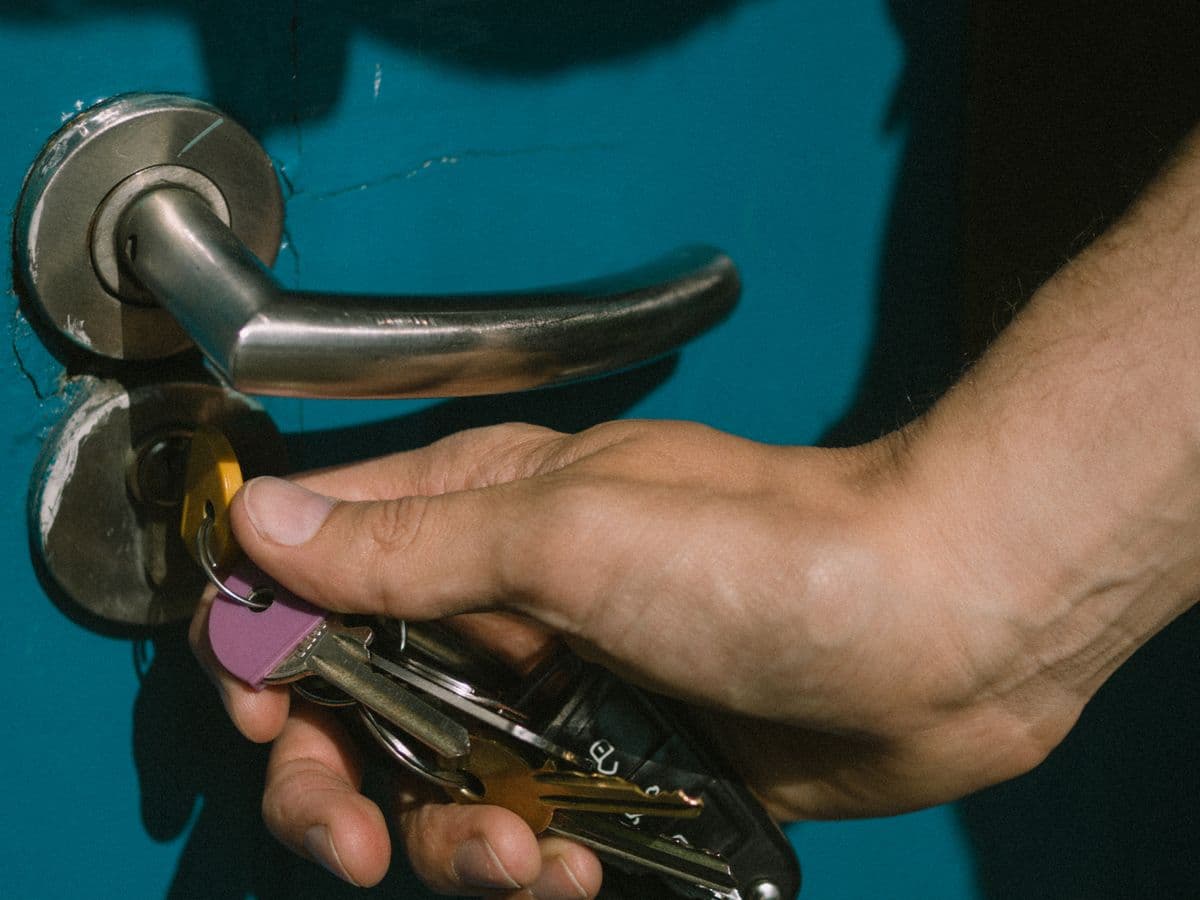 A hand unlocking the front door of an apartment